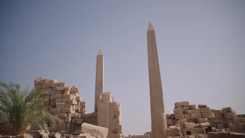 Ancient obelisks with carved hieroglyphics tower over the sun-drenched ruins of an Egyptian temple