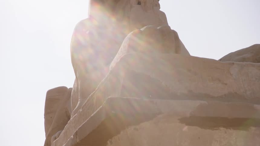 A majestic ancient Egyptian sphinx statue is revealed in slow motion with a powerful sun flare in the background