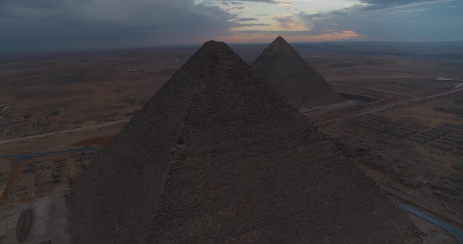A dramatic aerial view rising over the Great Pyramids of Giza at twilight