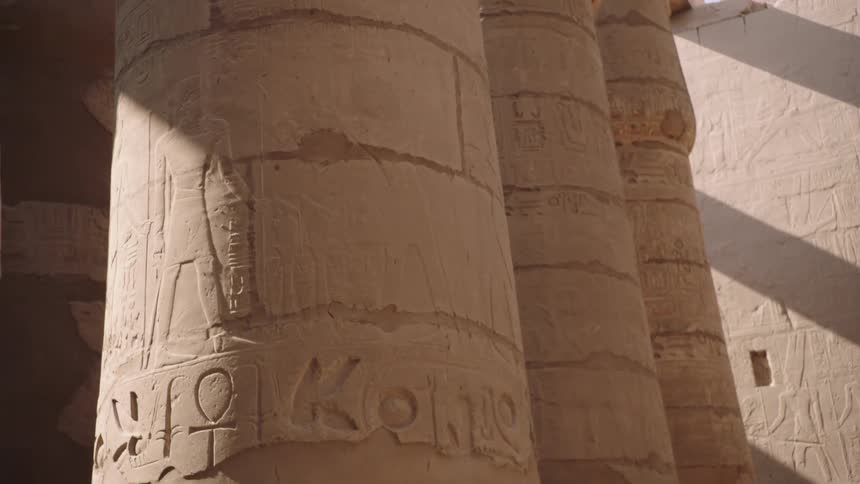 Slowly panning across the intricate hieroglyphics carved into the massive stone columns of an ancient Egyptian temple