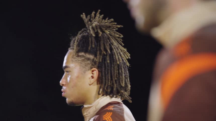 Slow motion profile of an intense young athlete with dreadlocks, sweating and focused during a nighttime competition
