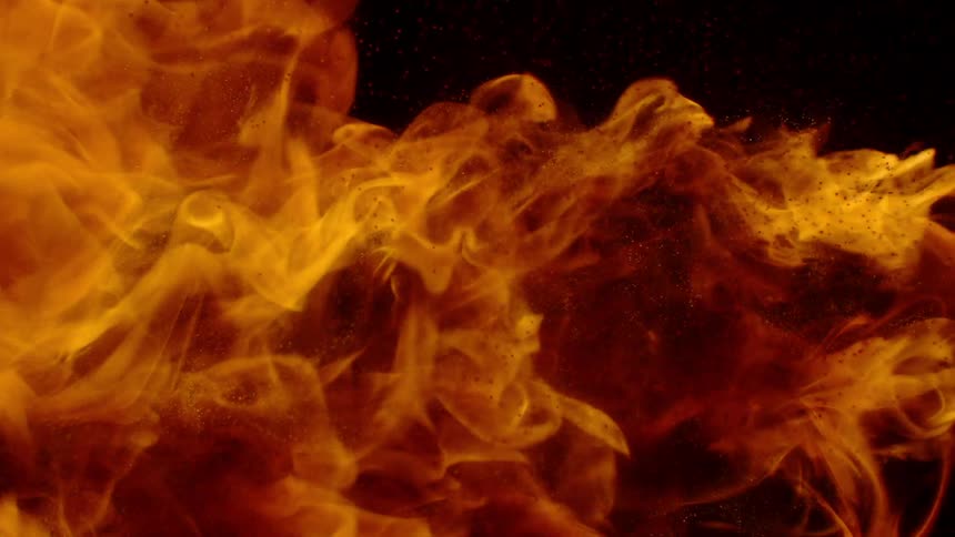 A large flame flares in a dark area