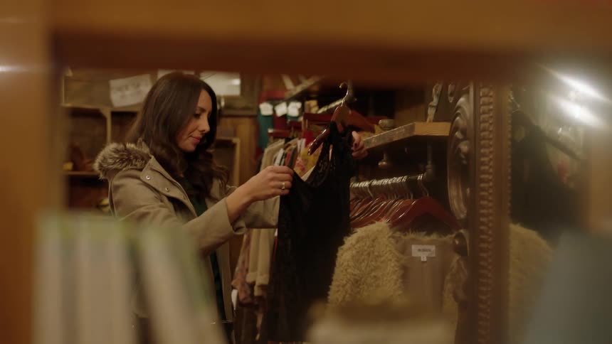 A woman is looking at a blouse in a shop