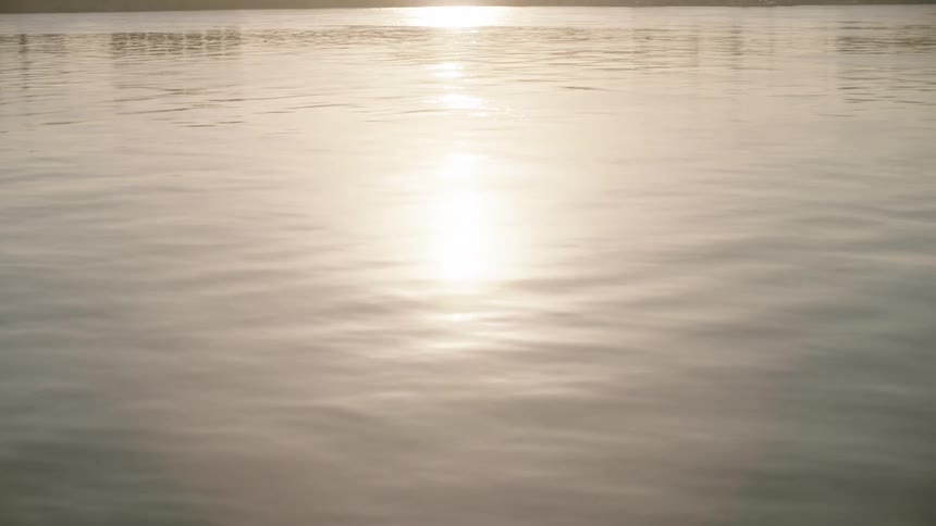 A serene view of the sun rising over the calm Nile River, with the ancient Luxor Temple silhouetted on the horizon