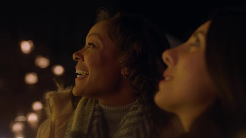 Two women talk together smiling at night