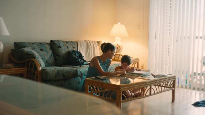 A loving mother and her young son spend a quiet afternoon drawing together on the floor in their sunlit living room