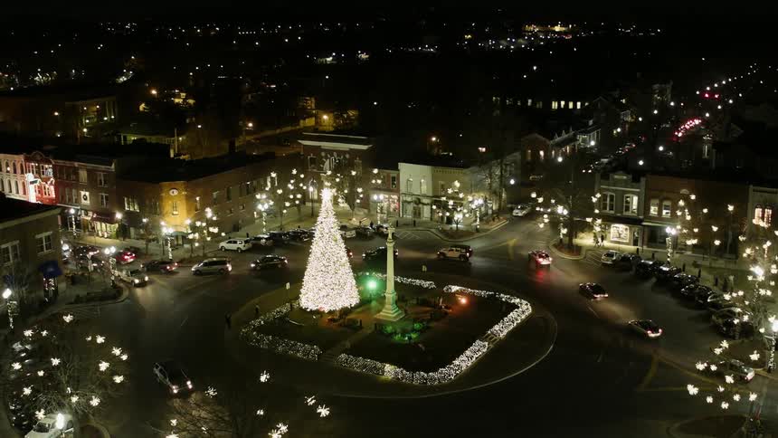 A large lit christmas tree stands in the center of a city rotary