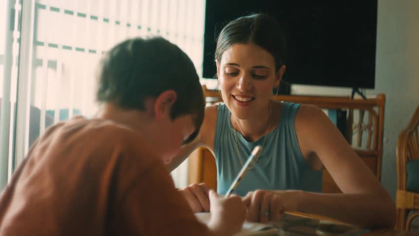 A loving mother helps her son with homework, sharing a happy and supportive moment at home