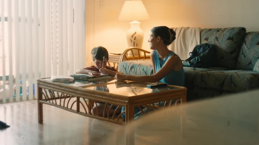 A loving mother helps her young son with his homework in their cozy living room, ending with a celebratory high-five