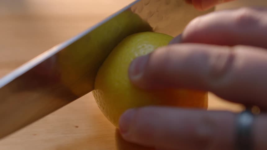 A person cuts the end off a lemon