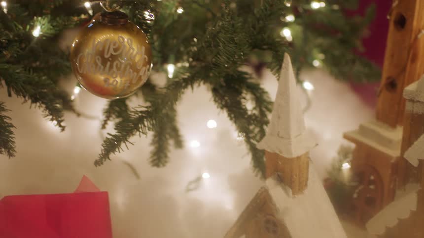 Toy houses are near a christmas tree