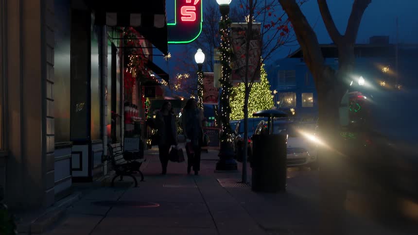 People walk down the sidewalk at night
