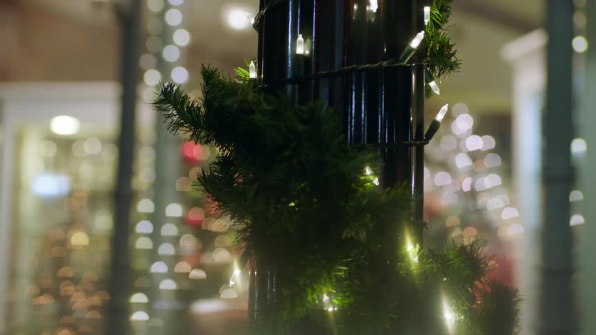 Christmas decorations are wrapped around a pole in a city at night