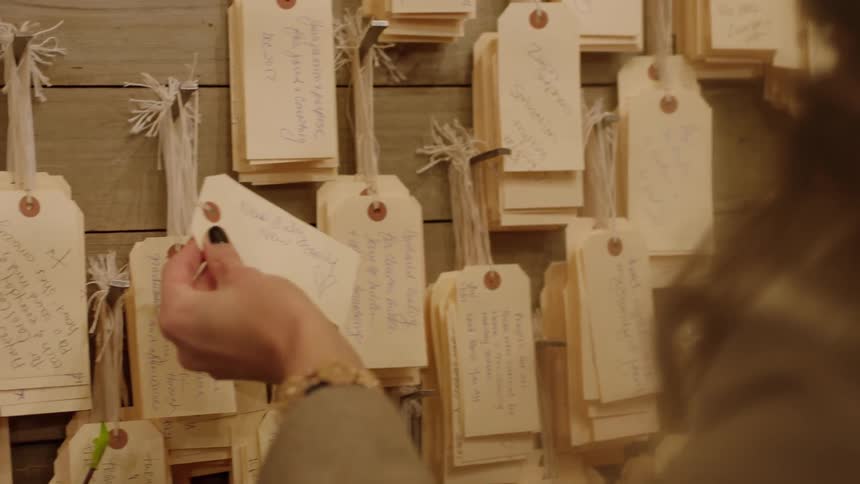 A woman reads a note written on a gift tag in a shop