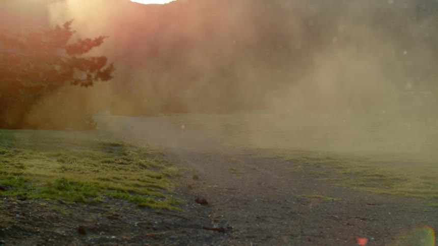 The field is surrounded by hills and covered with fog