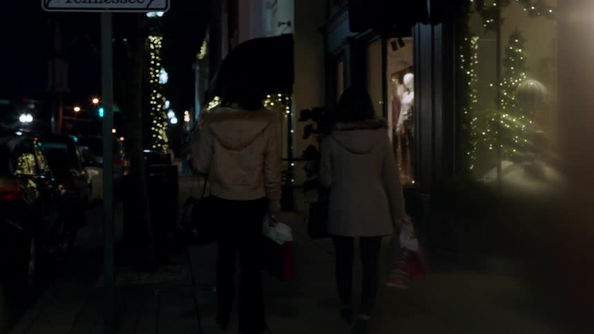 Women walk down a city sidewalk at christmastime