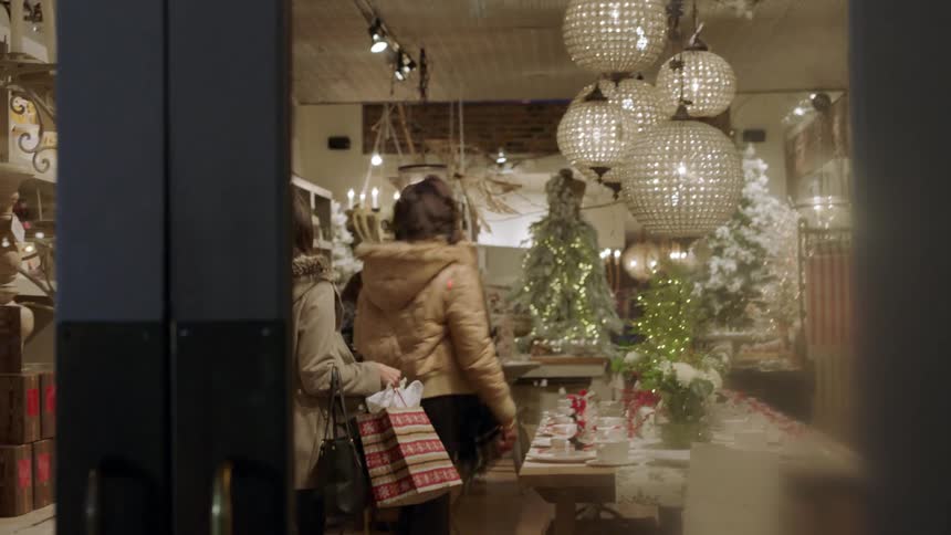 Two women look at dishes in a shop