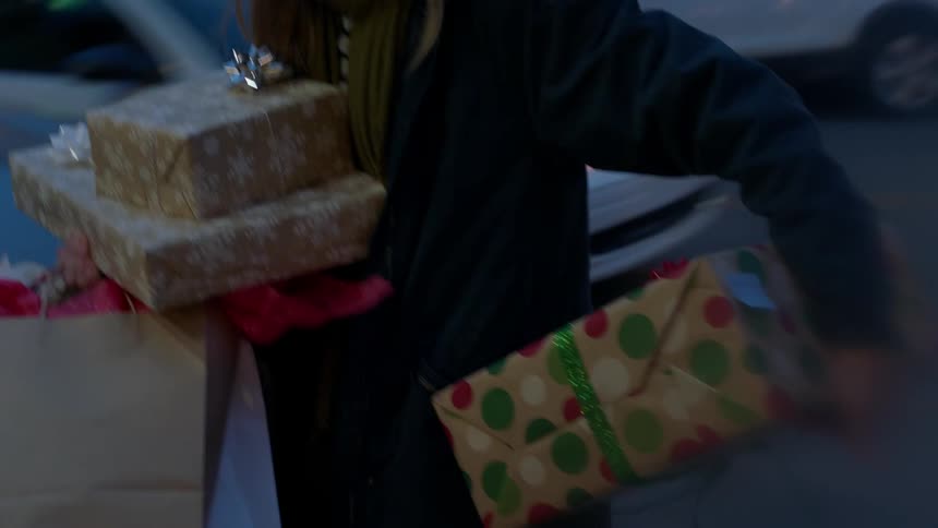 A person removes gifts from a car