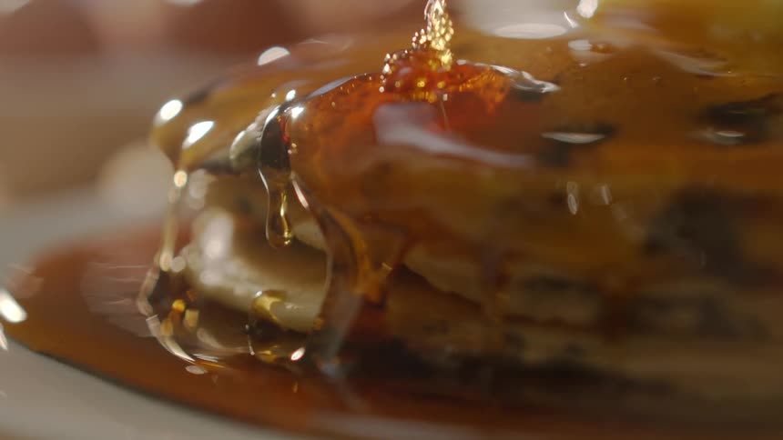Syrup is poured on a stack of pancakes