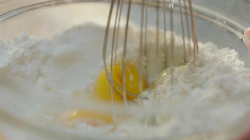 A whisk mixes flour and eggs
