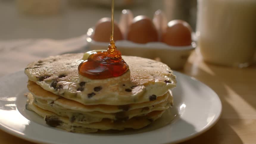 Syrup pouring onto a stack of blueberry pancakes