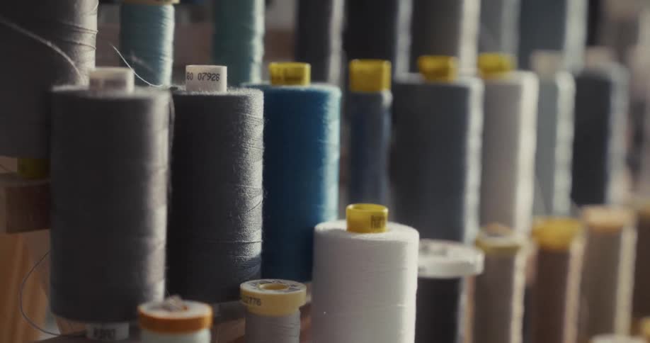 A close-up of multiple spools of colored thread arranged in a tailor's workshop