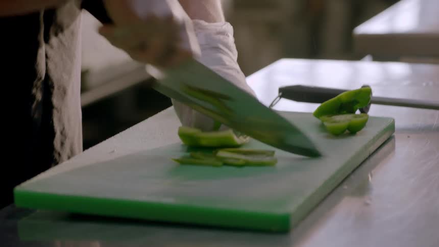 A chef is cutting bell pepper into slices