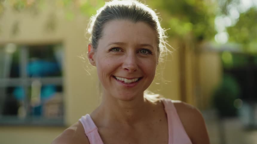 Portrait of a confident and happy middle-aged woman smiling warmly at the camera in a sunlit garden
