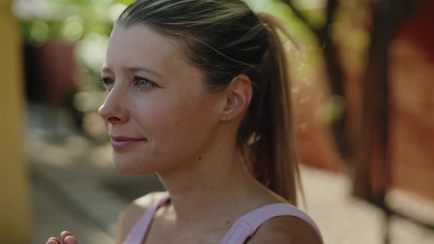 A serene woman with her hands in a prayer pose finds her center during a peaceful meditation in a sunlit garden