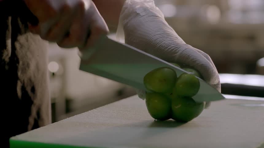 Person slicing a green pepper on cutting board in kitchen