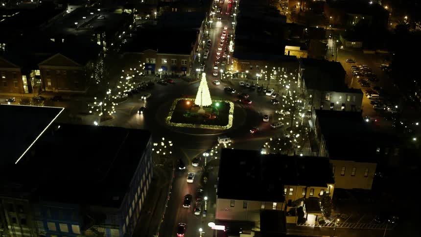 Cars travel around a rotary in a city square at night