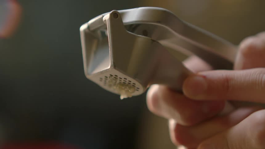 A person uses a garlic press