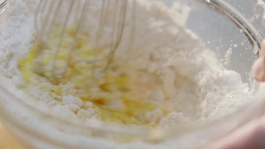 Person whisking eggs and batter in glass bowl