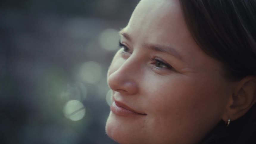 A beautiful woman with a gentle smile looks off into the distance, feeling content and peaceful