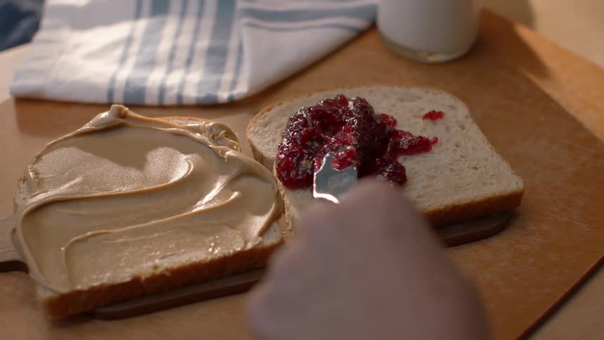 A person is making a peanut butter and jelly sandwich