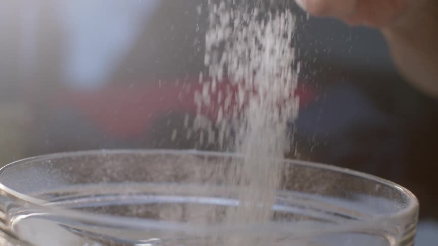 Person using sifter to sift flour into glass bowl