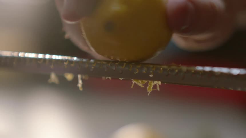 A person is shredding the peel on a lemon
