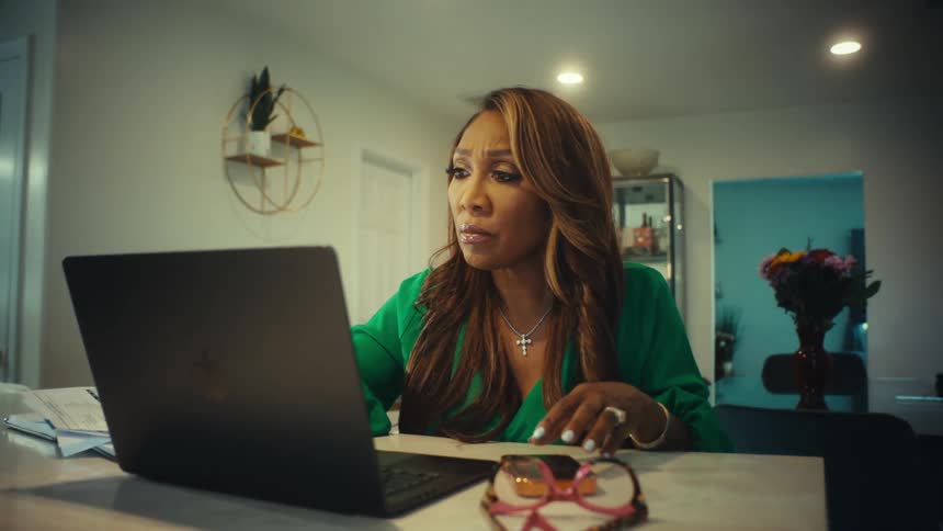 A woman working from home is shocked and then excited by the good news she sees on her laptop screen