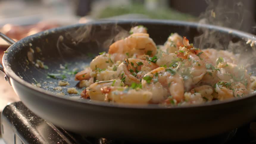 Shrimp cooks in a steamy skillet on the stove