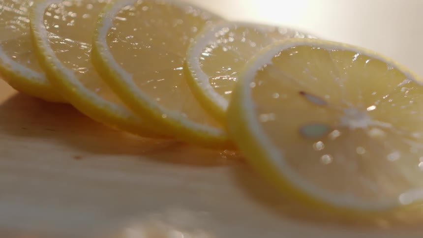 A lemon is cut into slivers on a board