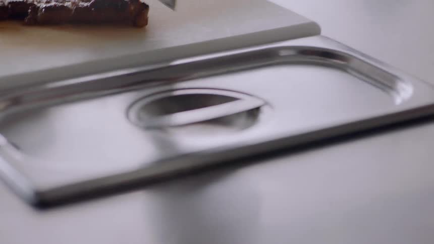 A person is cutting steak on a board