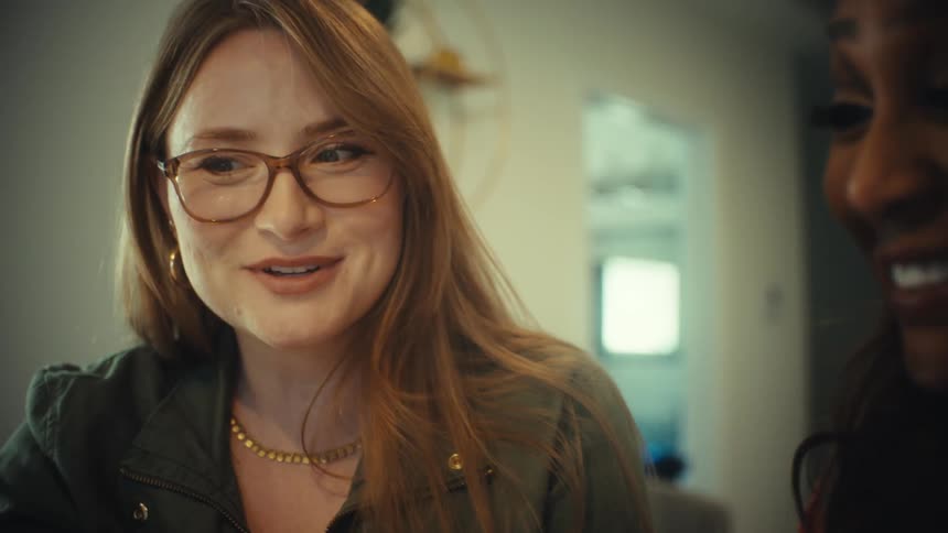 Close up shot of a woman with red hair wearing glasses having an engaging conversation with a friend