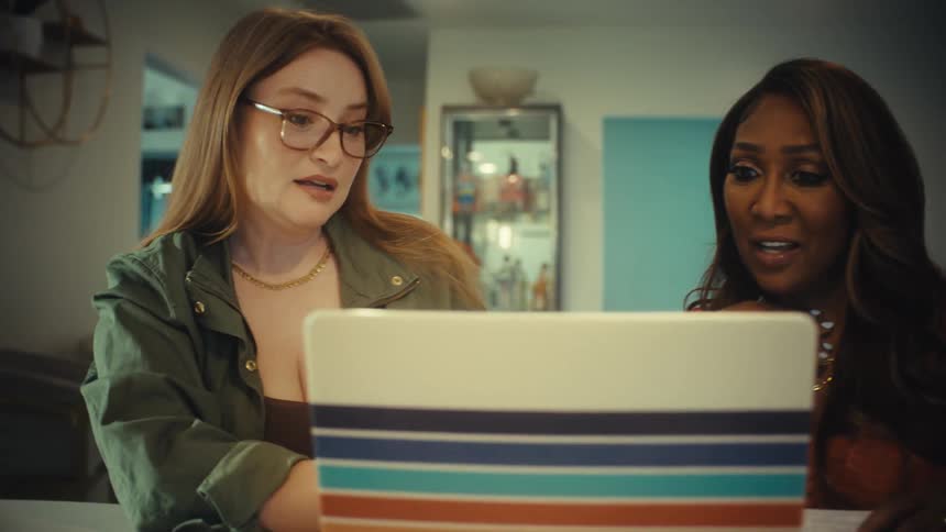 Two female business partners share an exciting moment before getting serious while collaborating on a laptop in a home office