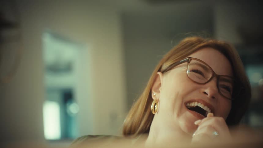 Close-up slow motion shot of two diverse women reacting with surprise and then joyous laughter while looking at a screen
