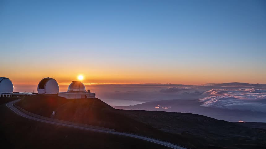 A stunning timelapse captures the sun setting behind the astronomical observatories on a mountain peak above the clouds
