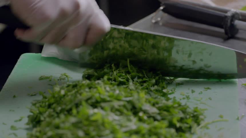 A person is cutting chives on a cutting board