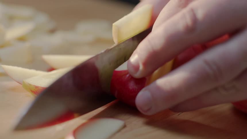 A man cut an apple on a cutting board