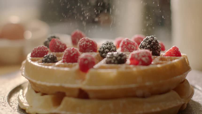 Powdered sugar is poured on waffles