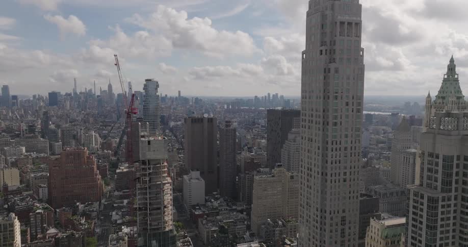 A drone pushes in towards the Manhattan skyline, passing skyscrapers before tilting down to a top-down view of the city streets