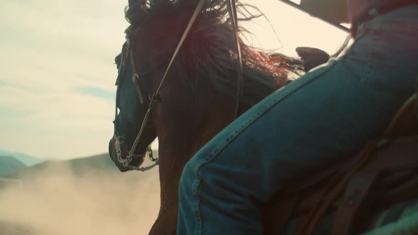 A cowboy holds the reins of a galloping horse